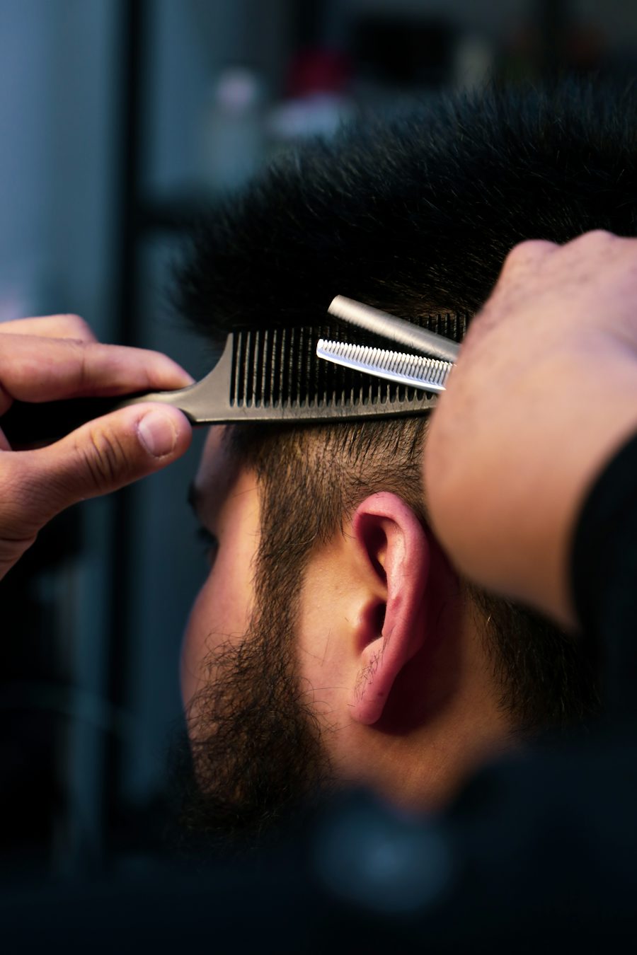 Comb and thinning shears trimming short dark hair