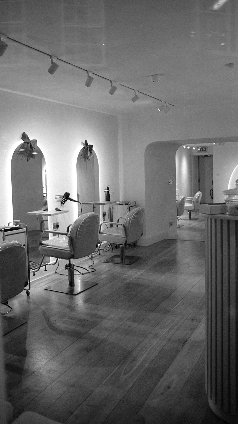 Black-and-white salon with white chairs and arched mirrors